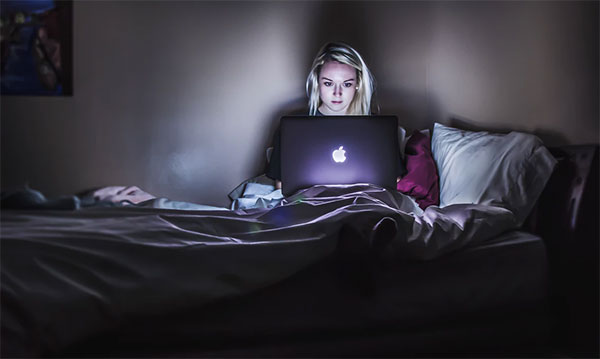 woman using a laptop on her bed  